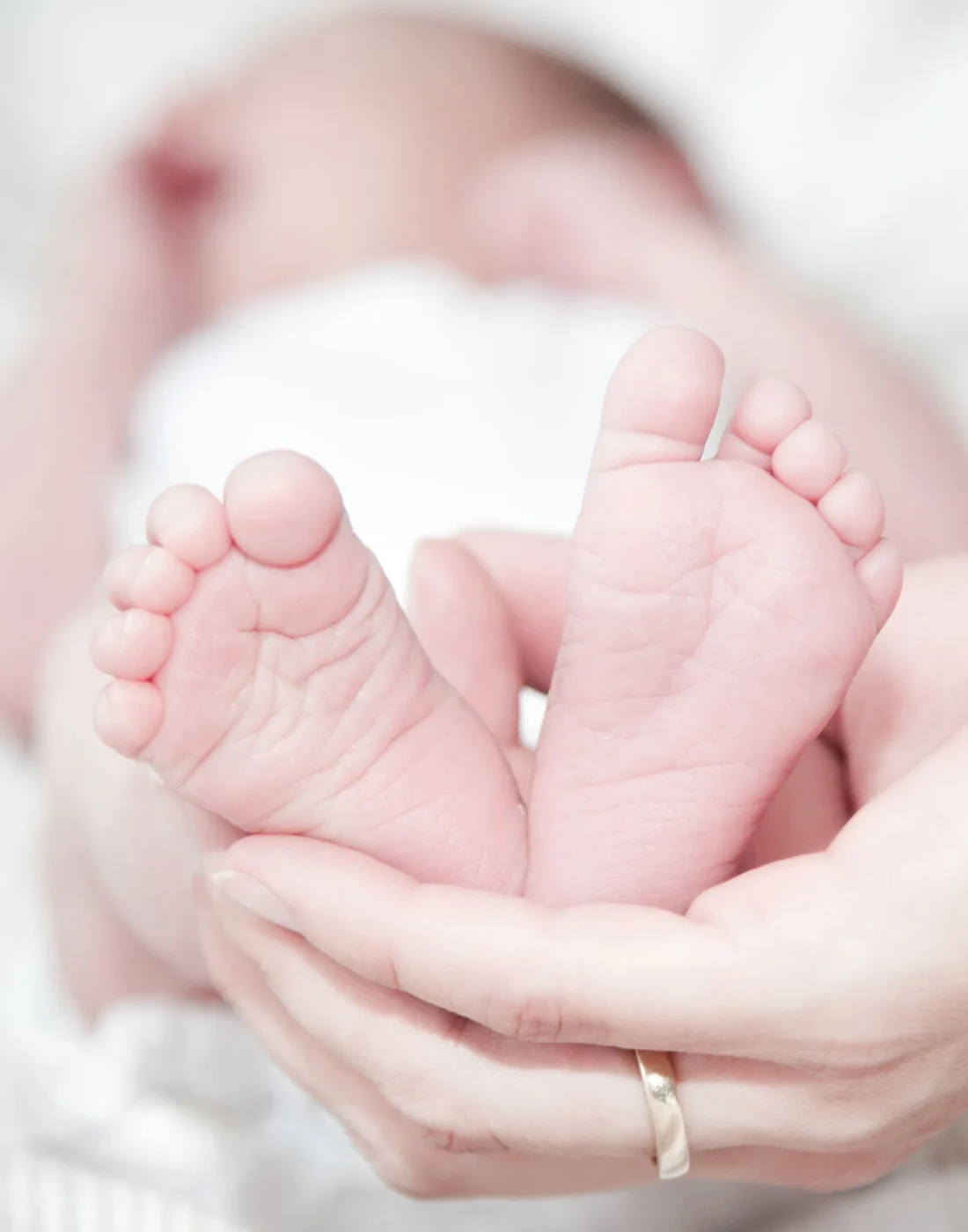 Manos de una madre sosteniendo los pies de su bebé recién nacido
