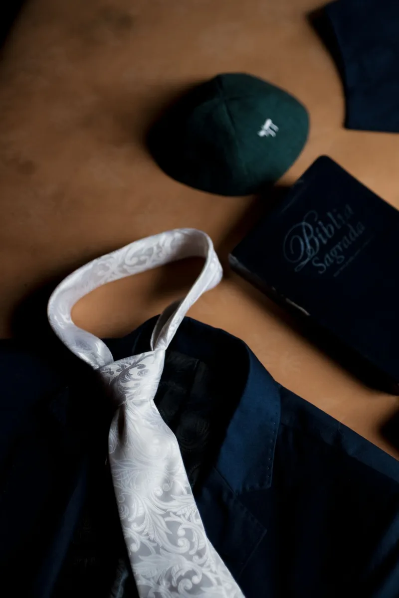 Traje, corbata, reloj y frasco de perfume dispuestos sobre la cama