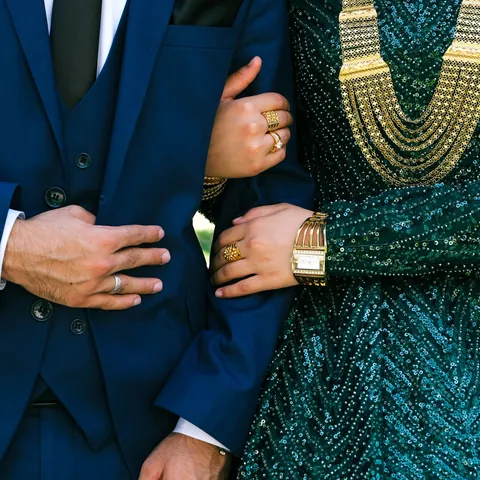 Padrinos de lazo, detalle de manos entrelazadas con anillos y joyería dorada