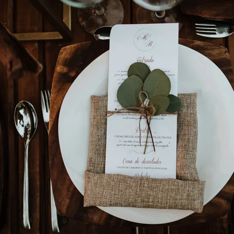 Tarjeta de menú con hojas de eucalipto sobre una mesa de madera