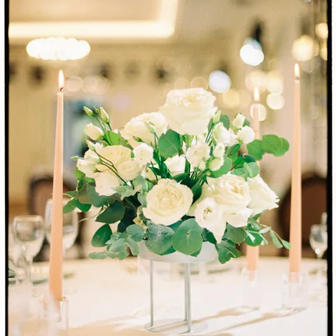 Centro de mesa de rosas blancas rodeado de velas