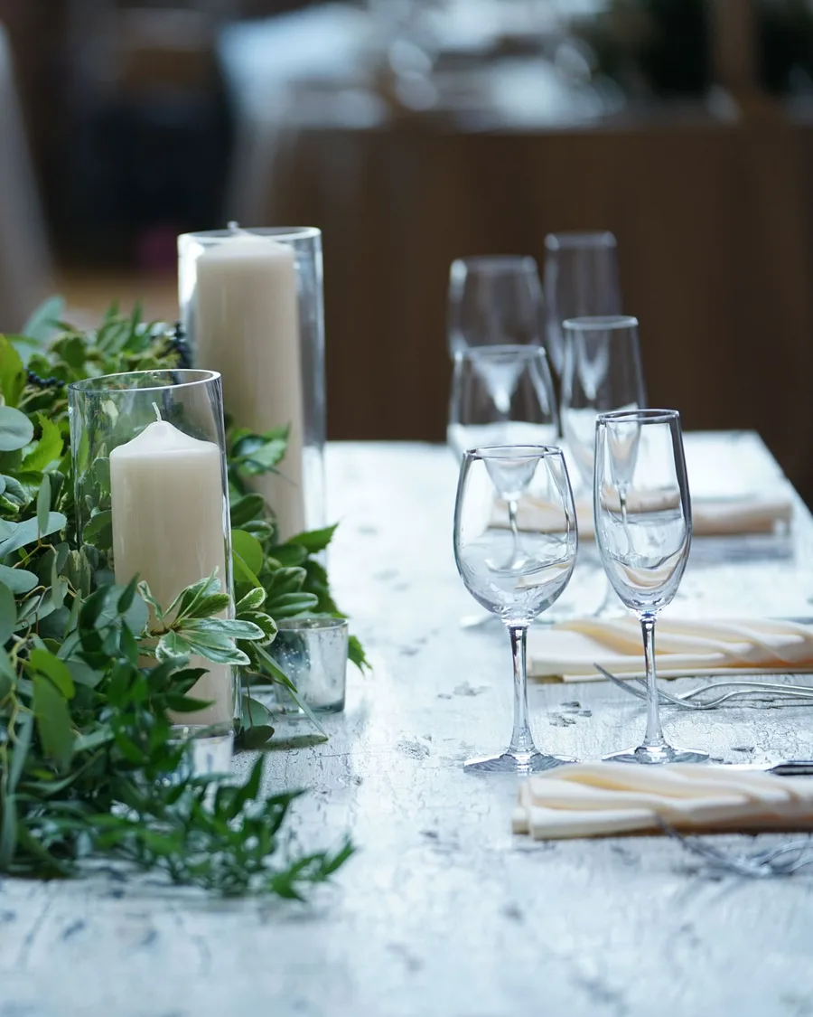 Mesa puesta con velas blancas, cristalería y eucalipto