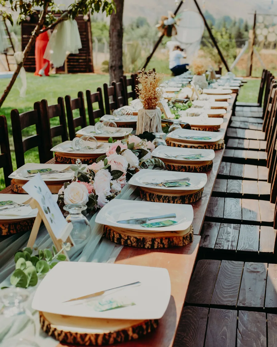 Mesa rústica de boda con vajilla, madera y arreglos florales