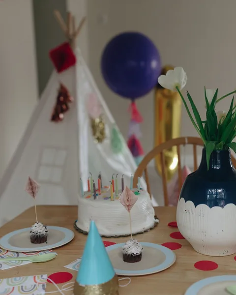 Mesa de cumpleaños con pastel, cupcakes y flores