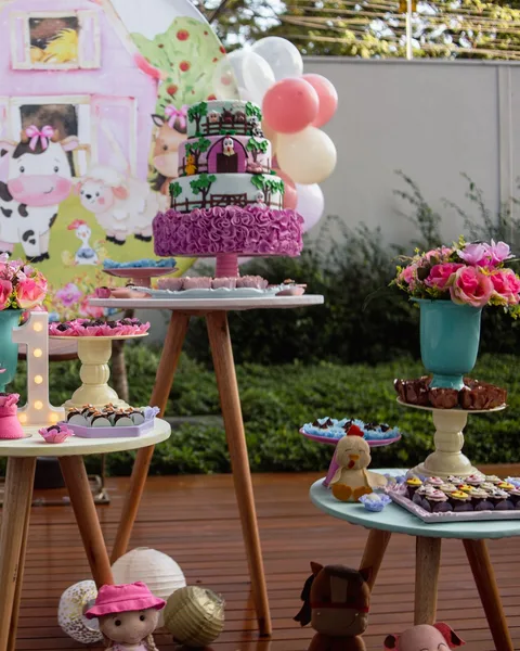 Mesa de fiesta con pastel, globos y golosinas al aire libre