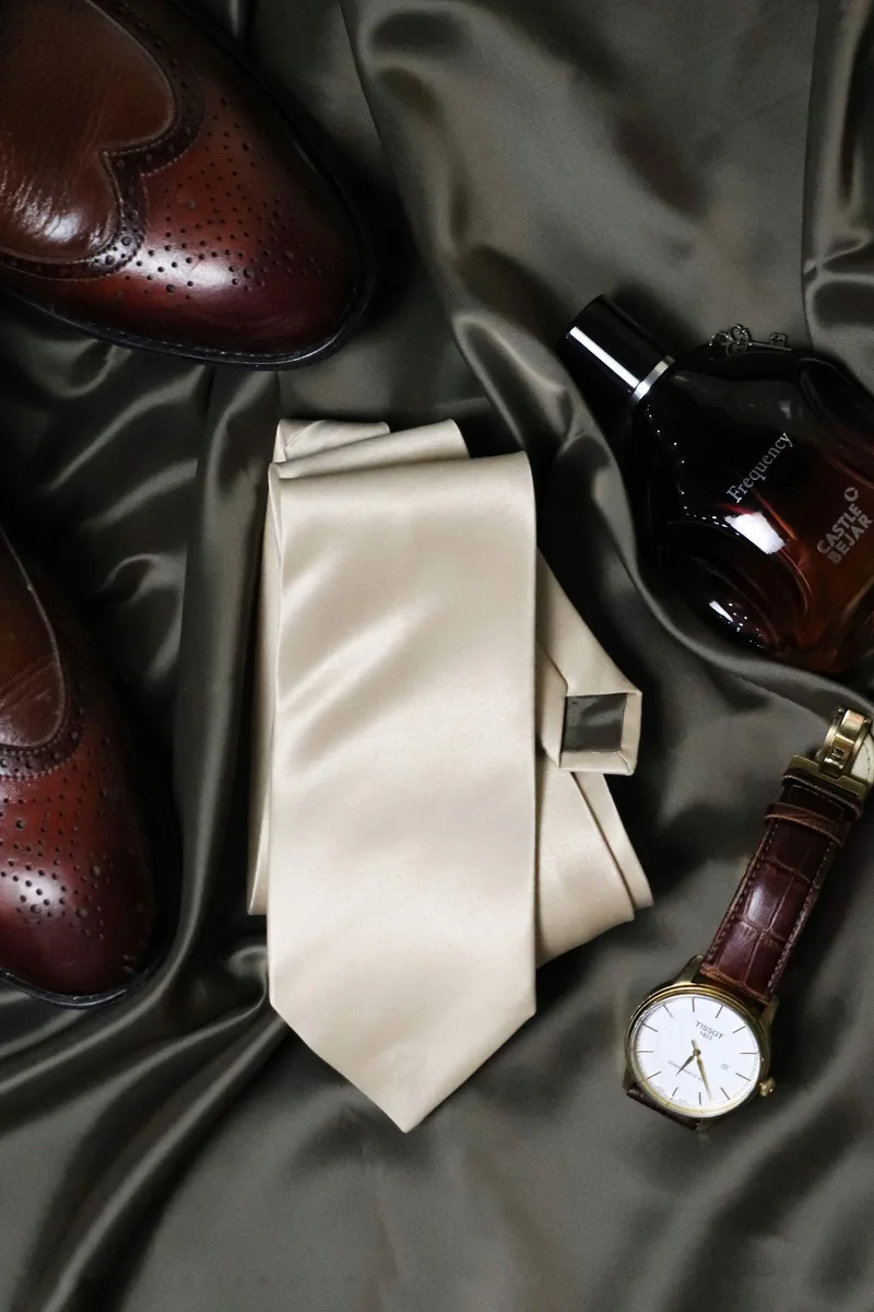 Corbata, reloj de bolsillo, gemelos y zapatos de vestir sobre tela oscura
