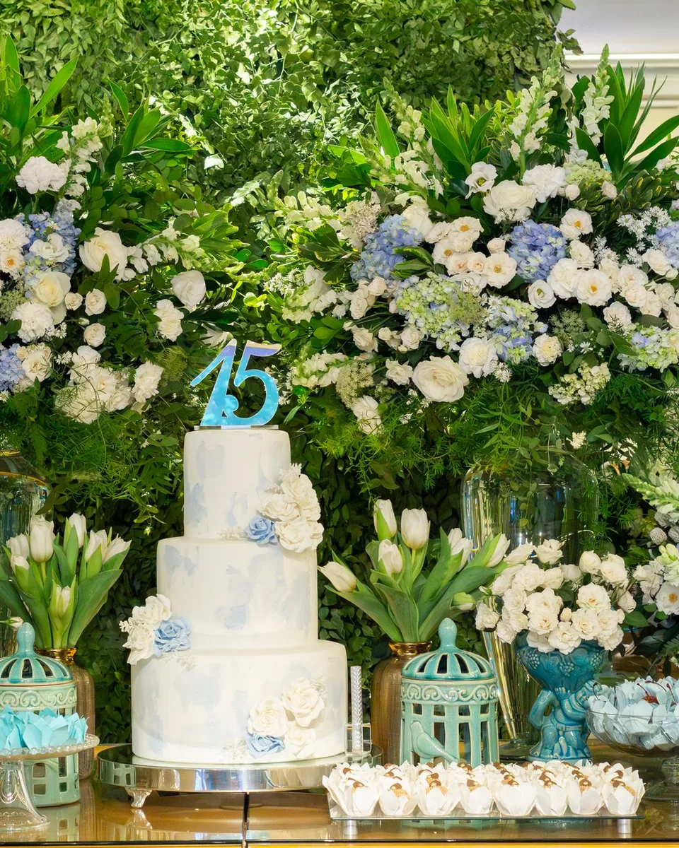 Pastel de quince años en azul y blanco entre arreglos de flores y tulipanes