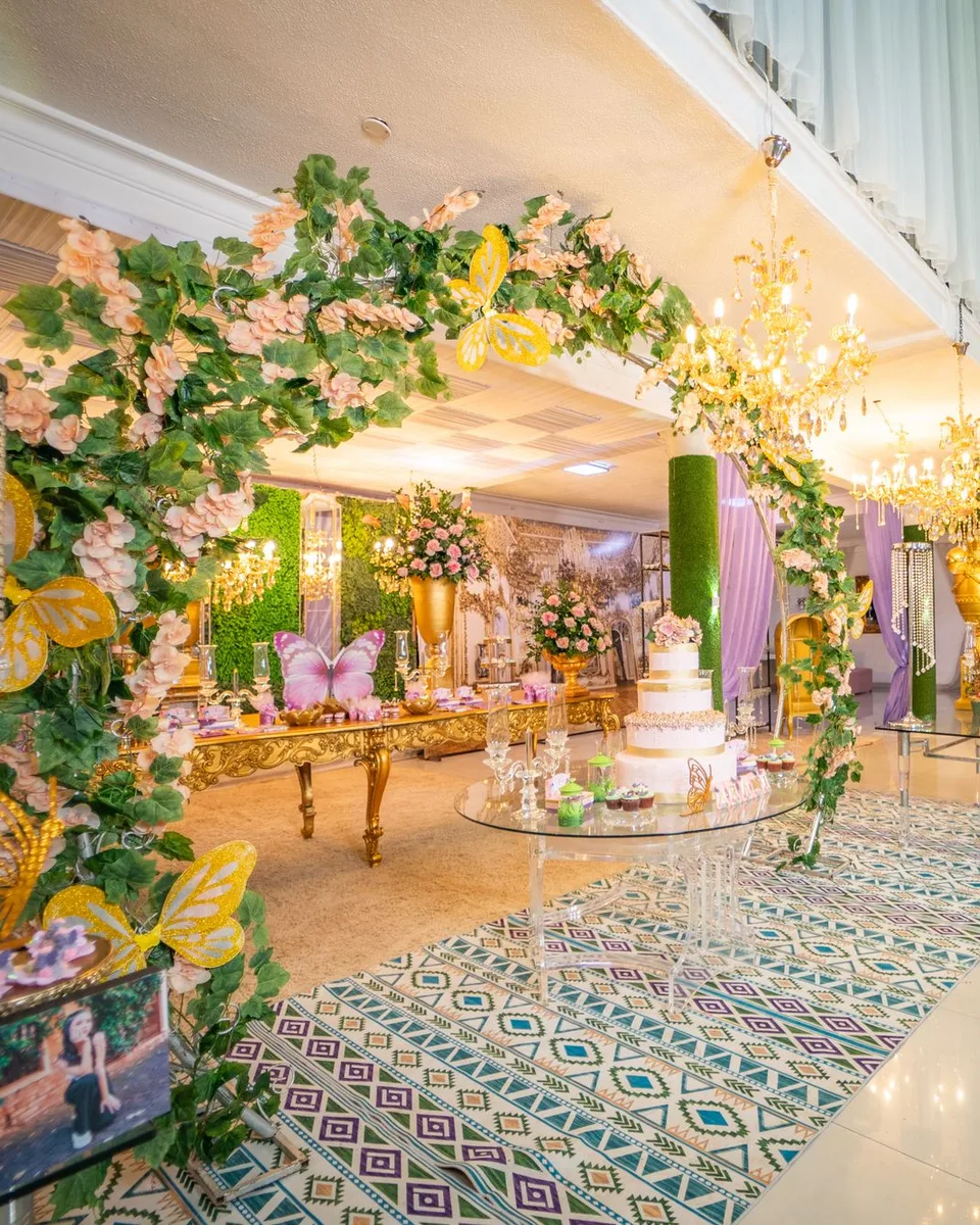 Salón decorado con arcos de follaje, flores blancas y luces cálidas