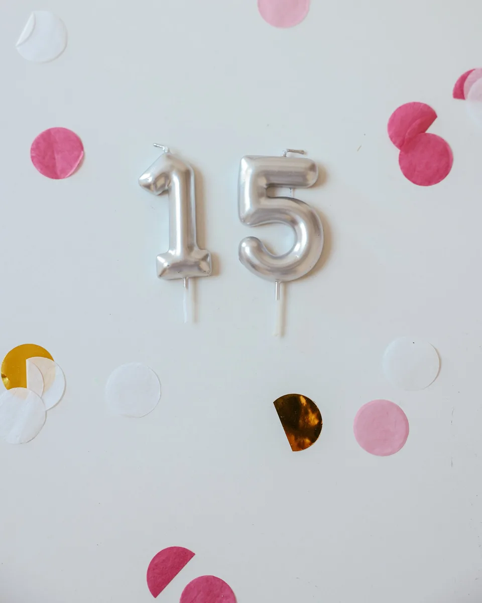 Velas plateadas con el número 15 sobre fondo blanco con confeti
